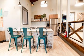 a kitchen with a counter and three blue chairs